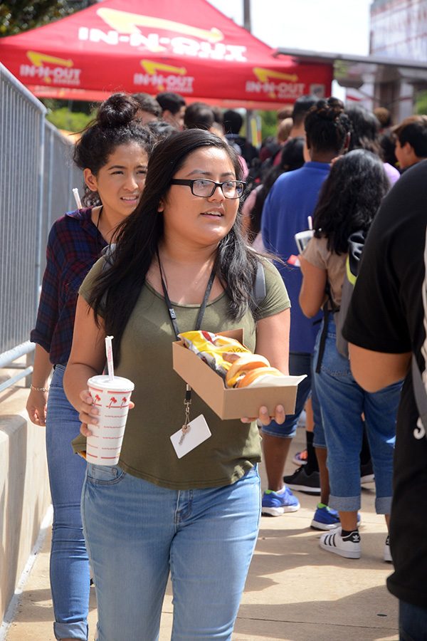 Senior Briseida Marcial-Cantero carefully balances her burger and chips while walking back inside from the food truck. The In-N-Out truck came to the school for an AVID fundraiser. Photo by Heiress Smith
