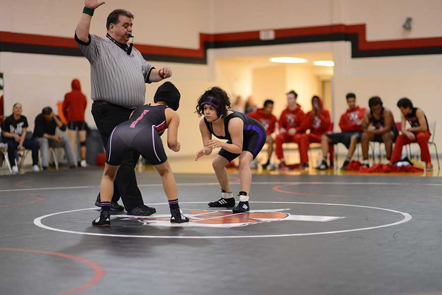 Senior Erika Torres crouches in preparation to defeat her opponent at a wrestling match. Photo by Alisia Cabrera