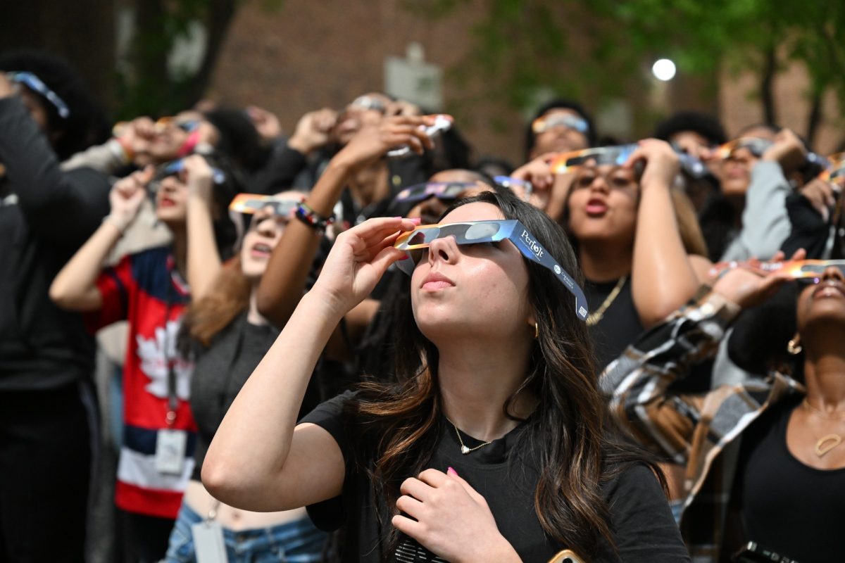 Freshman Hannah Hodges watches the solar eclipse as it reaches totality with classmates in the parking lot outside od D-hall. It was the first time since 1878 where Dallas was in the path of totality, and it wont occur again for 300 years. Photo by Leilani Gilmer Photo credit: Leilani Gilmer