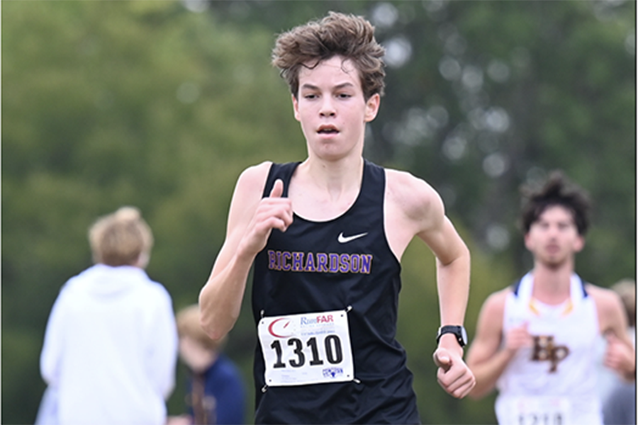 At the district cross country meet, Head Coach Aleyh Christopher gives encouragement to Harris Cohorn as he approaches the finish line.