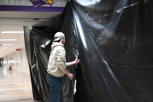 DECA President Thatcher Bartlett lifting the tarp to see the construction of the Roost. Talon photo by Ilan Ahmed.