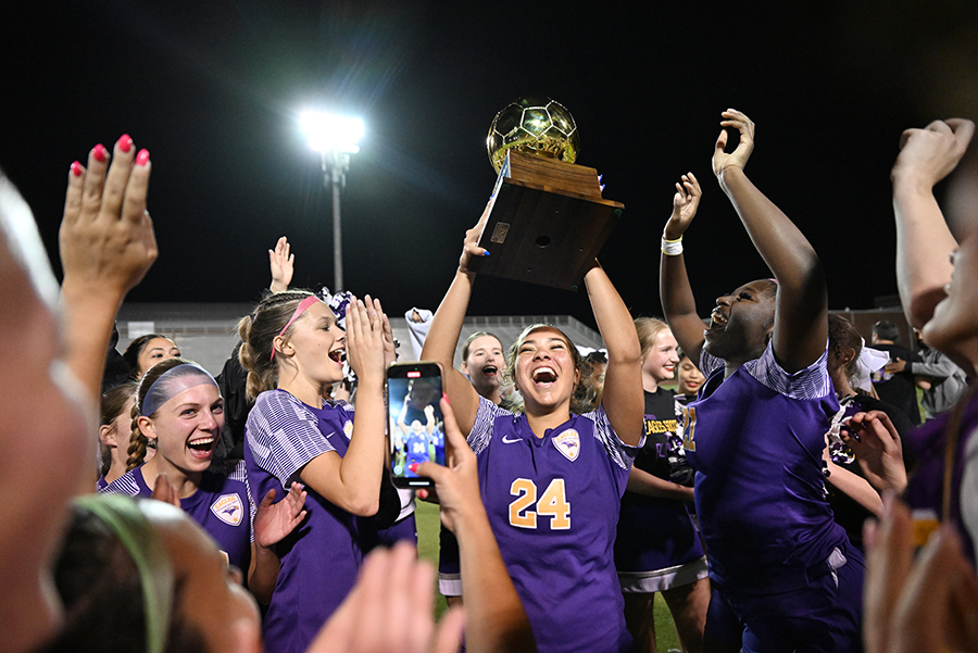Senior Winnie Goodson holds up the Bi-District championship trophy while celebrating with teammates. Talon photo by Henry Fair