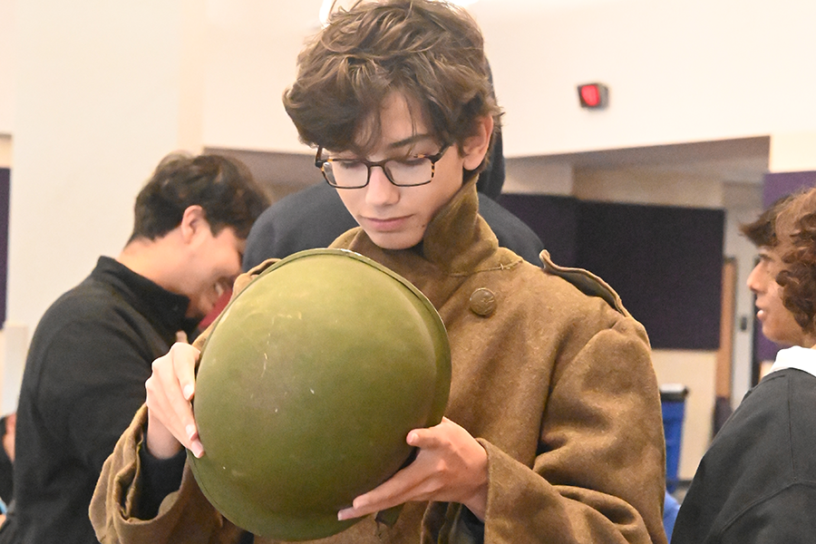 Junior Brady Wolff inspects a World War 2 helmet during an artifact exhibition for his US history class assignment. U.S. History teacher Benjamin Prior organized an exhibit displaying his collection of real WWII artifacts for U.S. History students to have a more hands-on learning experience. "I think students need to understand the history is not just something that you saw on a PowerPoint, 
it's not just something you read in a book, these are real people that lead real lives," Prior said. Talon photo by Lucio Vargas Stoyanoff