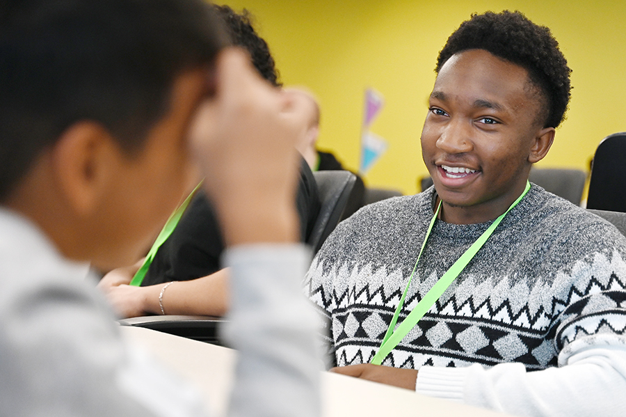 Senior Sam Moyo works with his MST elementary school partner before StateFarm workers start presenting. MST Magnet elementary and RHS Computer Science Magnet students worked together to create applications centered around helping the community as part of the Capstone Computer Science Magnet project. "I think at first it seemed like most of the high school kids were a little nervous about working with elementary school kids because it's a little bit out of their element, but after they've met a few times and worked with them they're really working well together," Compsci Magnet teacher John Poston said. Talon photo by Lucio Vargas Stoyanoff