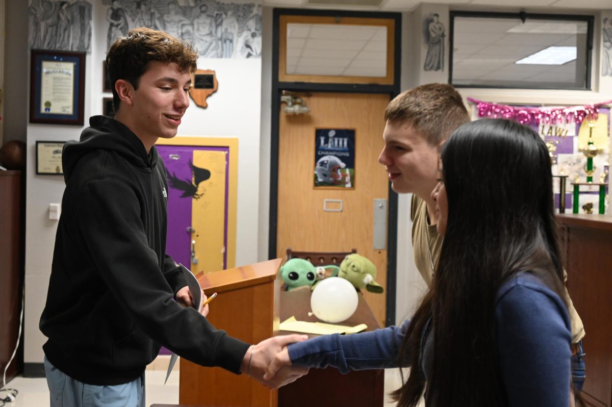 Sophomore Logan Daniel shakes hands with sophomore Estrella Cruz before they begin negotiating the sale of widgets. Talon photo by Ilan Ahmed