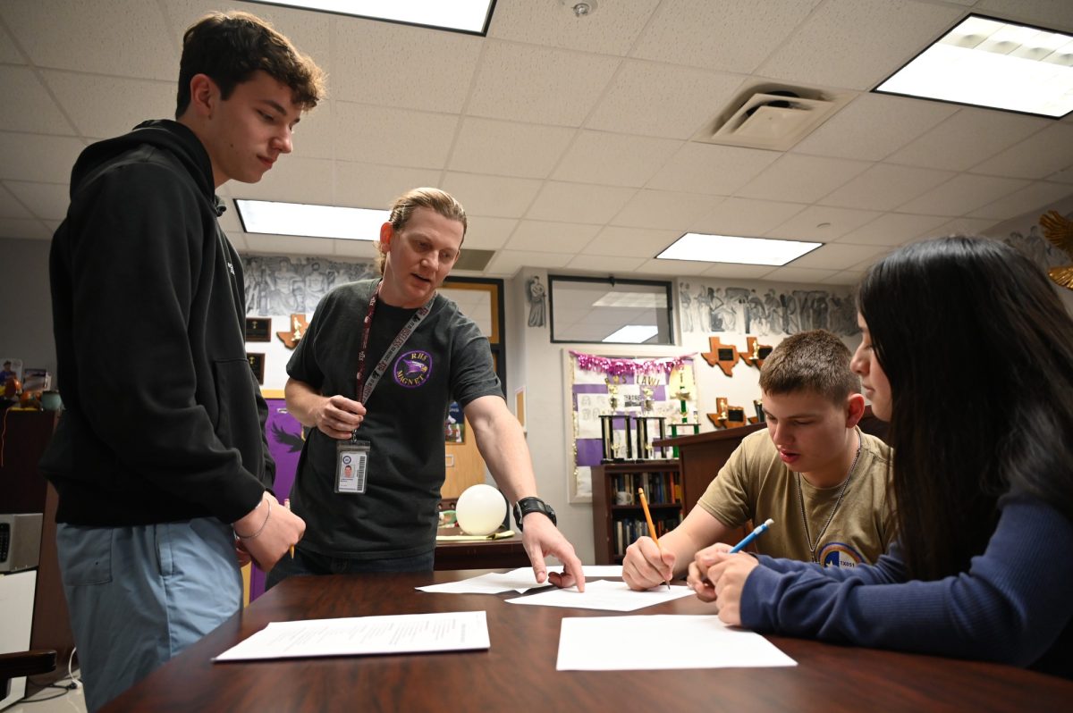 Law Magnet teacher Christopher Bufkin points to where sophomores Logan Daniel, John Andrews and Estrella Cruz should explain why they were unable to reach an agreement over the sale of widgets. After spending a semester learning about contract law, Law Magnet teacher Christopher Bufkin created a game for his sophomore magnet students to practice negotiation and to understand the steps to create a contract. "The point of it is that it's okay to walk away," Bufkin said. "If you don't feel like you can make that deal, walk away." Talon photo by Ilan Ahmed