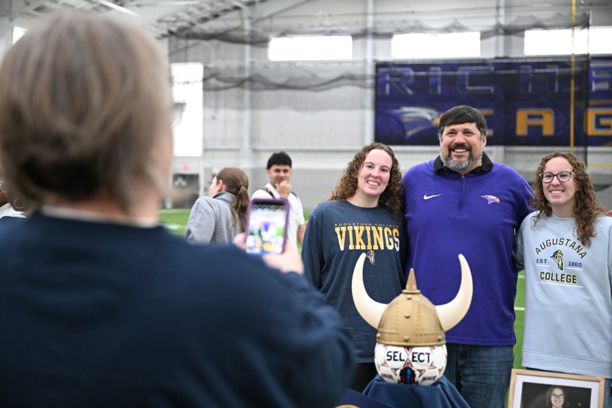 Seniors Carson Jarvis and Sloane Jarvis pose with the soccer coach Trey Pearce as their mom, girls wrestling coach Lisa Jarvis, takes a picture of them after they committed to Agustana College at Athletic Signing Day. Sloane and Carson are twin sisters who play varsity soccer and basketball together, while managing overlapping seasons and maintaining their academic responsibilities. "It's a lot of fun," Carson said. "We love being together and playing sports together." Talon photo by Henry Fair