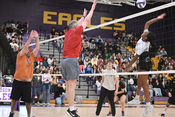 Junior volleyball player Mackenzie Ratcliff jumps to spike the ball over the net as volleyball coach Eric Miracle attempts to block it. Students won the first Student vs. Staff volleyball game since 2019 by a score of 25-23 in both sets yesterday during eighth period in the large gym. "We had a good turnout, and I thought everybody played hard," Miracle said. Talon photo by Edgar Perez