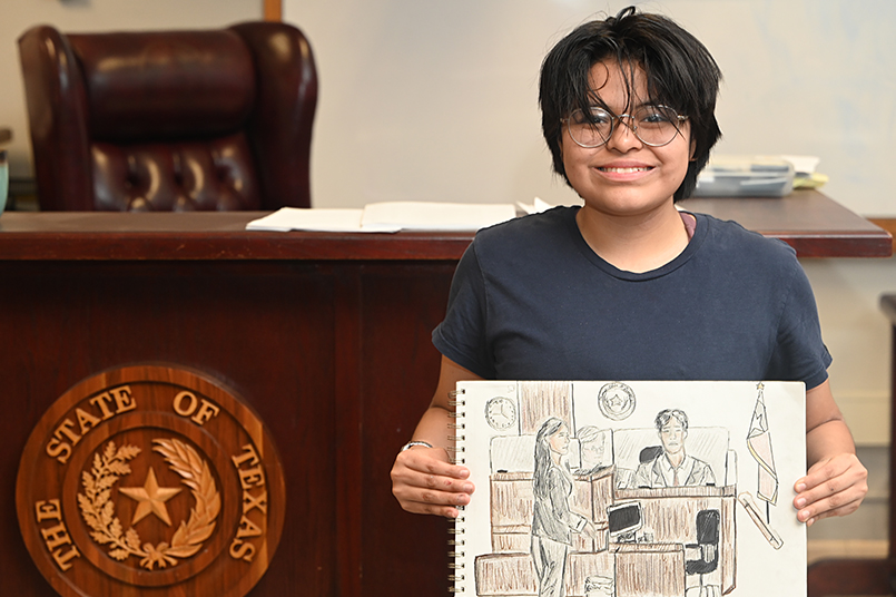 Art Magnet junior August Mexico holds up one of the sketches he created at the George Allen's courthouse competition for Mock Trial. Mexico is the courtroom sketch artist for mock trial this year and advanced to state where he was considered a "wildcard" because he advanced without his team. "My dream is to be a lawyer, but to be a courtroom artist, that combines both of my interests in law and art," Mexico said. Talon photo by Ryker Pearson