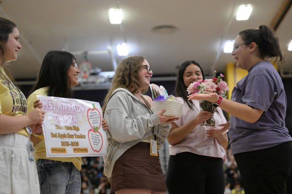 Freshman Leah Hilou, sophomore Emily Palma Salazar,and junior Alondra Soto hand dance teacher Nataly Garza the "Red Apple Teacher of the Year" award. Garza was awarded the "Red Apple First Year Teacher of the Year," given to one first year teacher at each campus, during the Student vs. Staff volleyball game. "I did not know I was nominated," Garza said. "I didn't even know it was an award. It felt so just like unreal in the moment." Talon photo by Xaviar Sheehan
