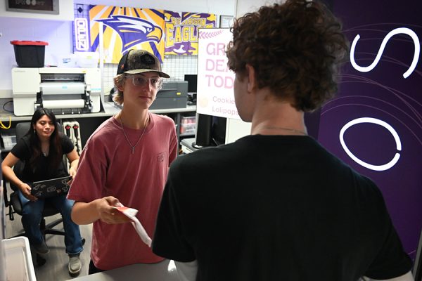 Sophomore Brooks Blair hands a bag of Chick-Fil-A cookies to a customer in the Perch before school started. DECA earned Gold Recertification on February 27th for its two student-run school stores, The Perch and The Roost, allowing them to continue running both stores and raising money for the program. "We started them for opportunities for students to have learning opportunities, hands-on running their own business," DECA Adviser Lee Geffert said. Talon photo by Xaviar Sheehan